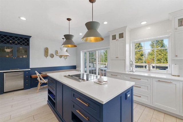 kitchen featuring blue cabinets, refrigerator, a kitchen island, white cabinetry, and light countertops