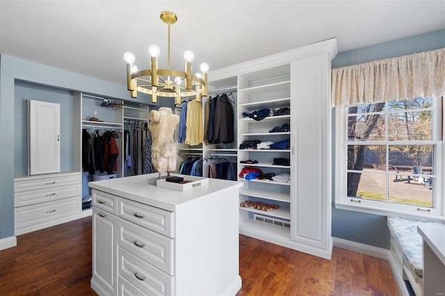 spacious closet with dark wood-type flooring and an inviting chandelier