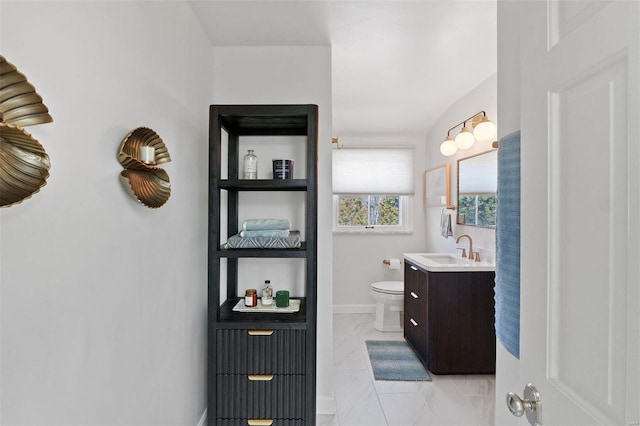 bathroom featuring toilet, marble finish floor, vanity, and baseboards