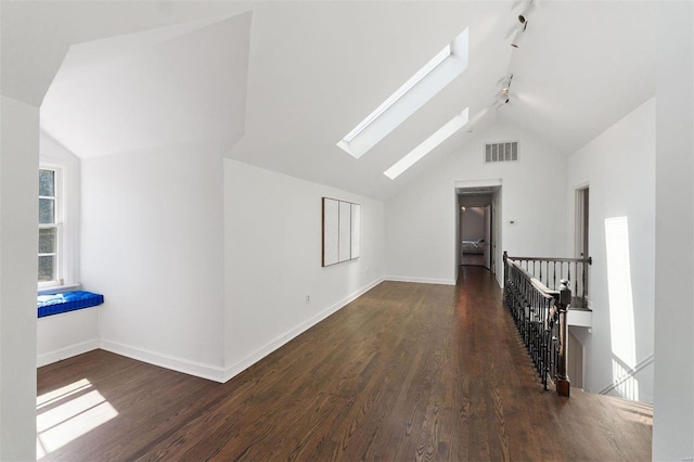 additional living space with lofted ceiling with skylight, baseboards, visible vents, and wood finished floors