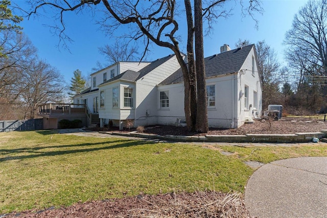 view of side of property featuring stairway, a chimney, a lawn, and a deck