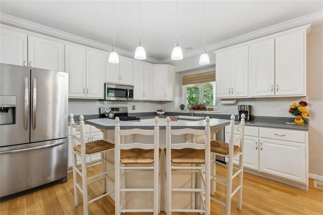 kitchen featuring dark countertops, appliances with stainless steel finishes, white cabinets, and decorative light fixtures