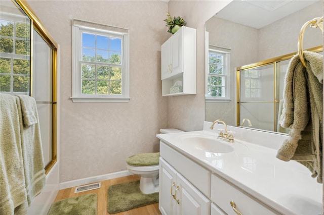 full bath featuring enclosed tub / shower combo, toilet, wood finished floors, visible vents, and vanity