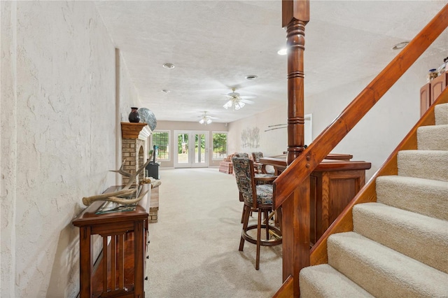 stairs with carpet floors, a fireplace, and a ceiling fan