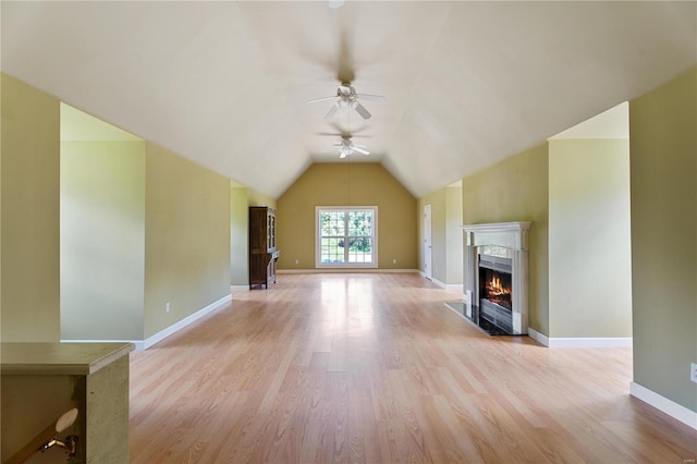 unfurnished living room with ceiling fan, baseboards, a high end fireplace, and light wood-style floors