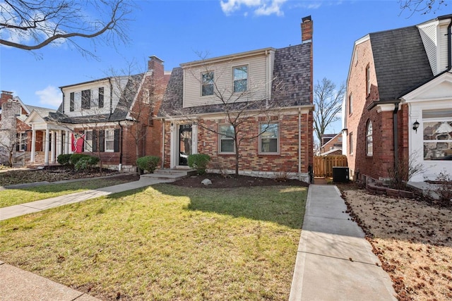 view of front facade with brick siding, a chimney, a shingled roof, central AC, and a front lawn