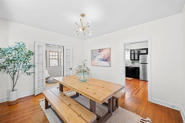 dining room with baseboards, light wood-style flooring, and a notable chandelier