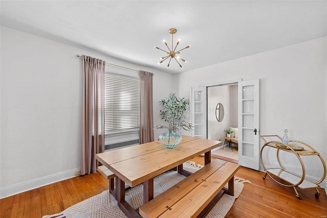 dining space with a notable chandelier, light wood-style flooring, and baseboards