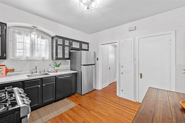 kitchen with dark cabinets, range with gas stovetop, dishwasher, and freestanding refrigerator