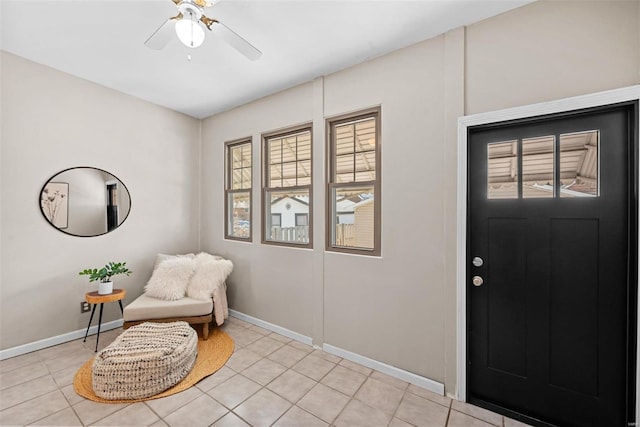 interior space with light tile patterned flooring, ceiling fan, and baseboards