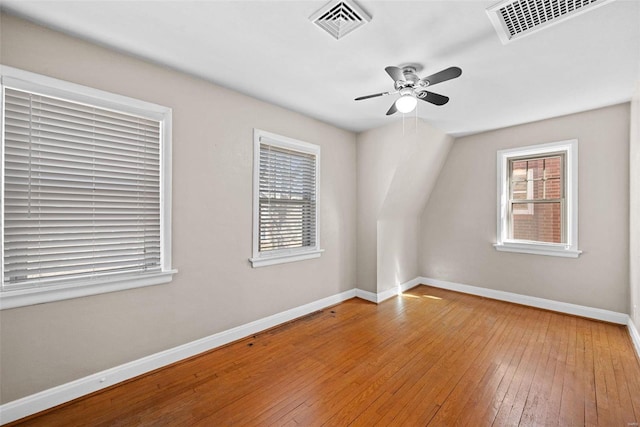 spare room with a ceiling fan, wood-type flooring, visible vents, and baseboards