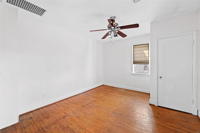 unfurnished room with hardwood / wood-style flooring, baseboards, visible vents, and ceiling fan