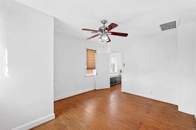 spare room featuring a ceiling fan, visible vents, baseboards, and hardwood / wood-style flooring