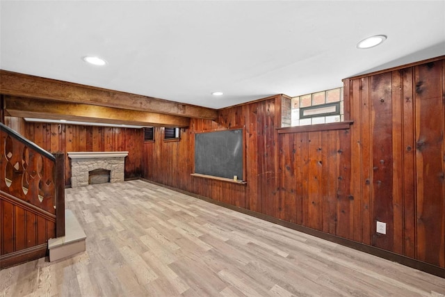 below grade area featuring wood walls, recessed lighting, wood finished floors, and a stone fireplace