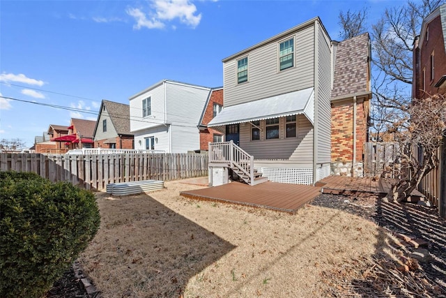 rear view of house with a fenced backyard, brick siding, and roof with shingles