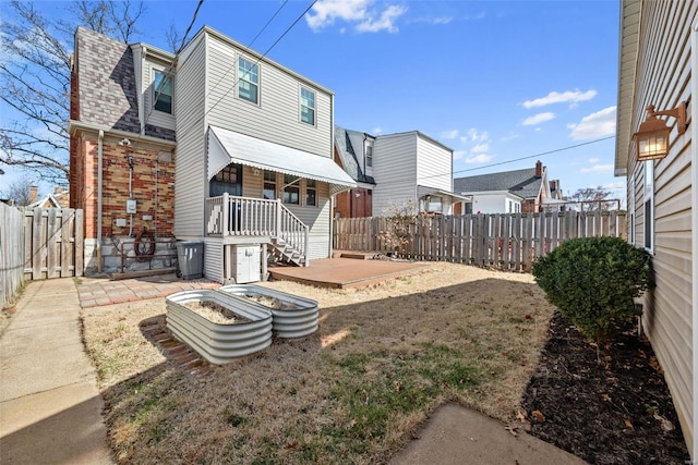 back of property with brick siding, roof with shingles, a fenced backyard, and a residential view