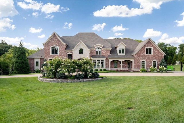 french provincial home featuring a front yard, brick siding, and driveway