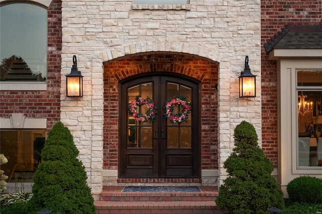 doorway to property featuring brick siding, stone siding, and french doors