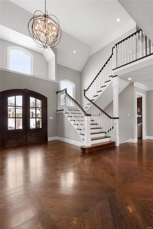 foyer featuring a notable chandelier, a high ceiling, baseboards, stairs, and french doors