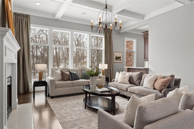 living room featuring coffered ceiling, ornamental molding, wood finished floors, an inviting chandelier, and beam ceiling