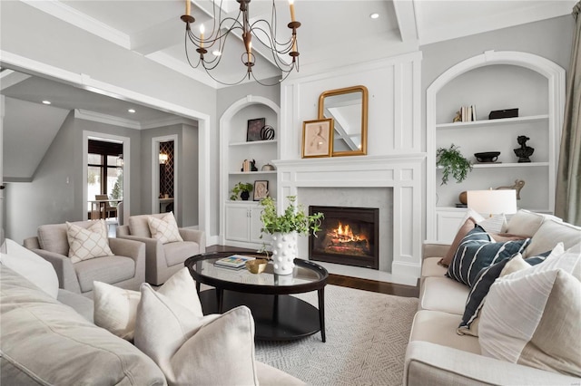 living area with built in features, wood finished floors, crown molding, a fireplace, and beam ceiling