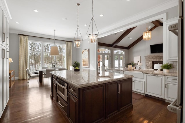 kitchen featuring a sink, a center island with sink, dark brown cabinets, and white cabinetry