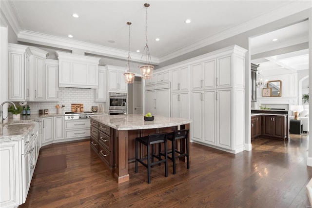 kitchen with appliances with stainless steel finishes, a center island, white cabinetry, and a sink