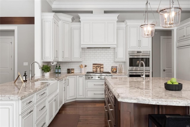 kitchen with decorative light fixtures, decorative backsplash, appliances with stainless steel finishes, a sink, and light stone countertops