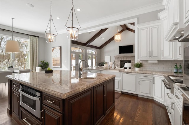 kitchen featuring hanging light fixtures, a sink, a kitchen island with sink, and dark brown cabinetry