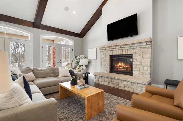 living area with a stone fireplace, wood finished floors, beamed ceiling, and french doors