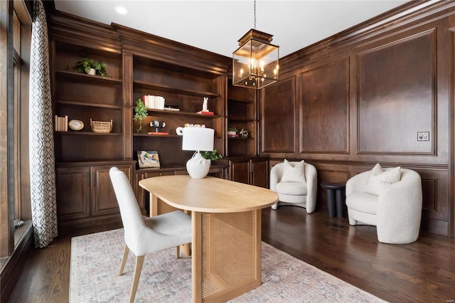 dining room with built in shelves, an inviting chandelier, dark wood finished floors, and a decorative wall