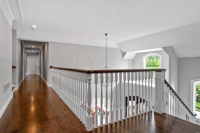 hallway featuring crown molding, dark wood finished floors, an upstairs landing, a chandelier, and baseboards