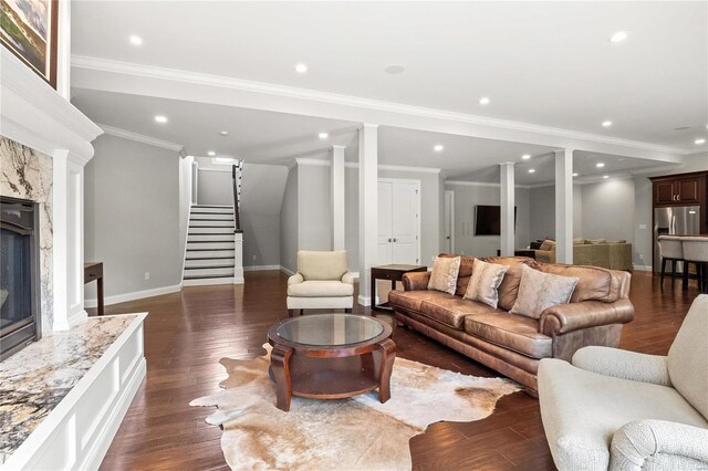 living room featuring dark wood-style flooring, ornate columns, stairway, a premium fireplace, and baseboards