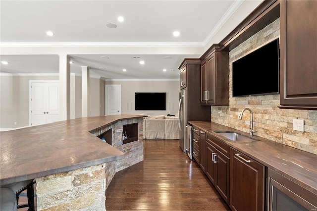 bar featuring dark wood-style flooring, tasteful backsplash, ornamental molding, freestanding refrigerator, and a sink