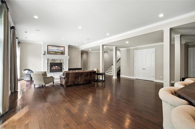 living room featuring a warm lit fireplace, stairway, dark wood finished floors, and baseboards