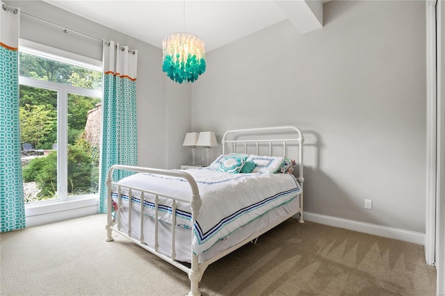 carpeted bedroom featuring baseboards and an inviting chandelier