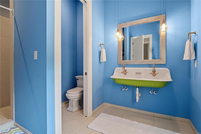 bathroom with a stall shower, tile patterned flooring, a sink, and toilet