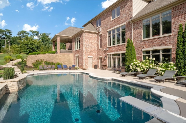 pool featuring fence, a patio, and a diving board