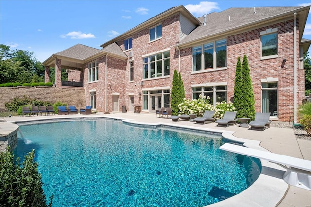 pool with a diving board, a patio, and fence