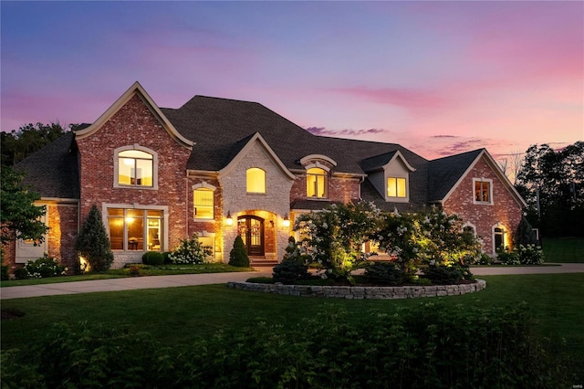 view of front facade with driveway, brick siding, and a yard