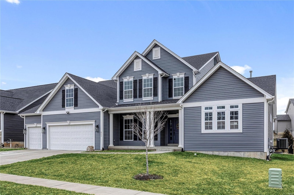 traditional home featuring central air condition unit, a porch, concrete driveway, an attached garage, and a front yard