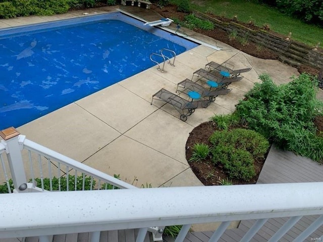 outdoor pool with a diving board and a patio