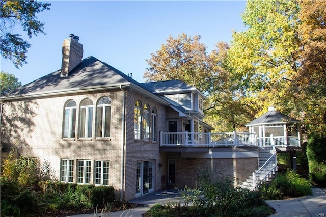 rear view of property featuring brick siding, a chimney, stairway, and a gazebo