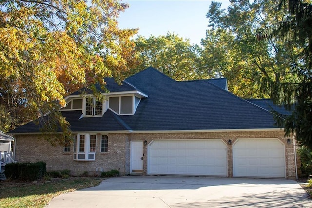 view of front of house featuring a shingled roof, concrete driveway, brick siding, and an attached garage