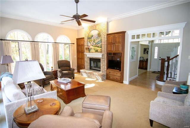 living room with crown molding, stairway, a brick fireplace, ceiling fan, and baseboards