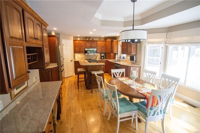 dining area with visible vents, a raised ceiling, ornamental molding, light wood-type flooring, and recessed lighting