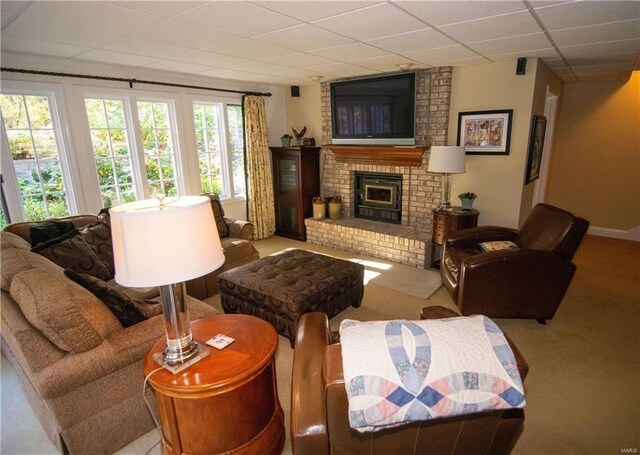 living area featuring a paneled ceiling, a brick fireplace, carpet, and baseboards