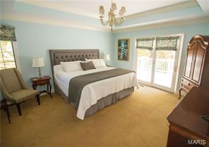 bedroom featuring access to outside, a tray ceiling, crown molding, and light colored carpet