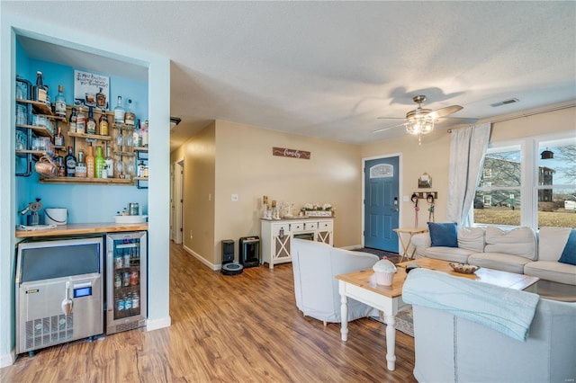 living room featuring beverage cooler, a dry bar, wood finished floors, and visible vents