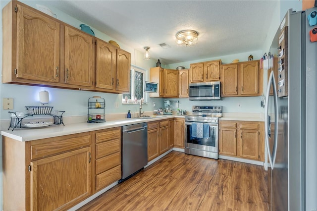 kitchen featuring visible vents, dark wood finished floors, appliances with stainless steel finishes, light countertops, and a sink